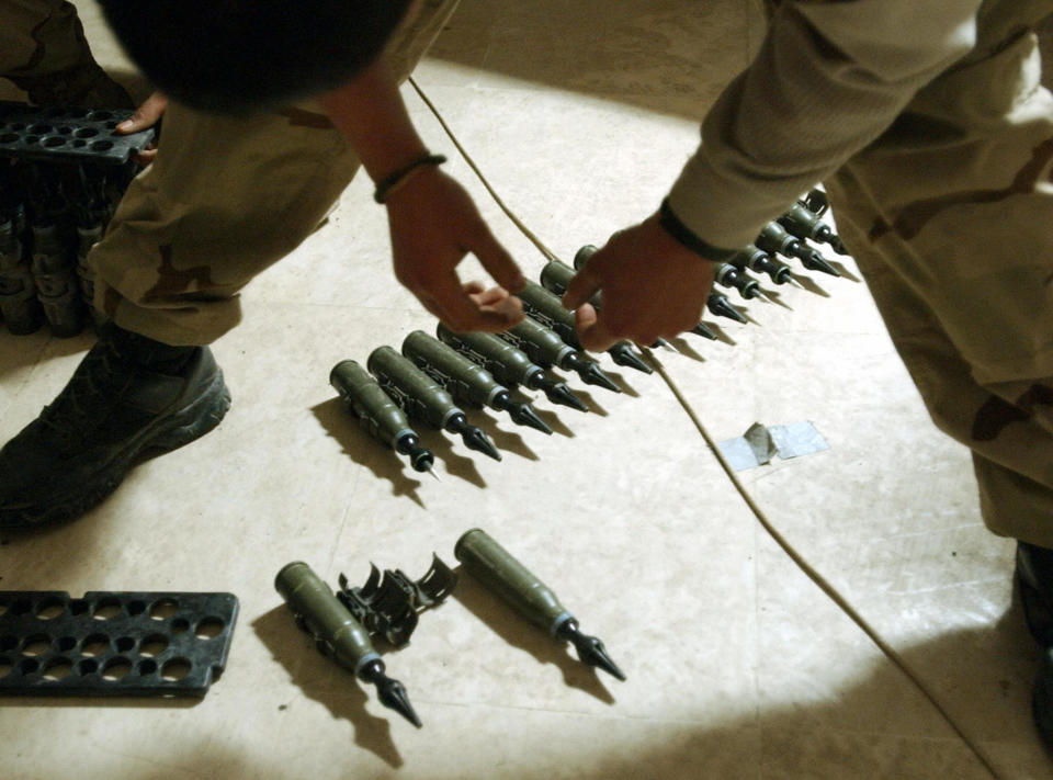 A U.S. Army specialist stands over 25 mm rounds of depleted uranium ammunition at his base in Tikrit, Iraq, in February 2004. (Photo: Stan Honda/AFP via Getty Images)