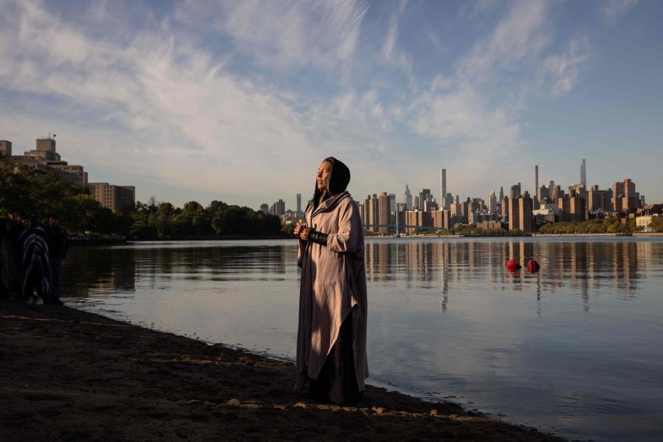 A woman prays while holding a container of water brought from Puerto Rico during an Indigenous Peoples' Day sunrise ceremony on Randall's Island in New York City on October 10, 2022. - The federal holiday to mark Columbus Day is also officially recognized as Indigenous Peoples' Day, following a proclamation by US President Joe Biden.