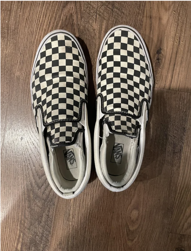 Smaller matching shoes inside an adult pair of black-and-white checkered loafers