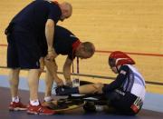 Britain's Philip Hindes sits on the ground after falling during their track cycling men's team sprint qualifying heats at the Velodrome during the London 2012 Olympic Games August 2, 2012. The officials had to assist Hindes as his left foot remained clipped in after the fall.