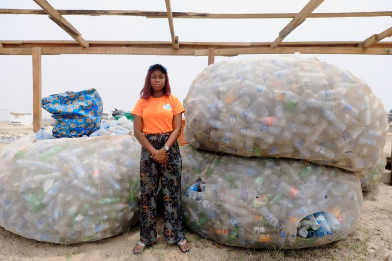 An Environmentalist, Doyinsola Ogunye poses for a portrait, standing in front of bags of P.E.T bottles picked from the shore at the beach in Lagos, Nigeria