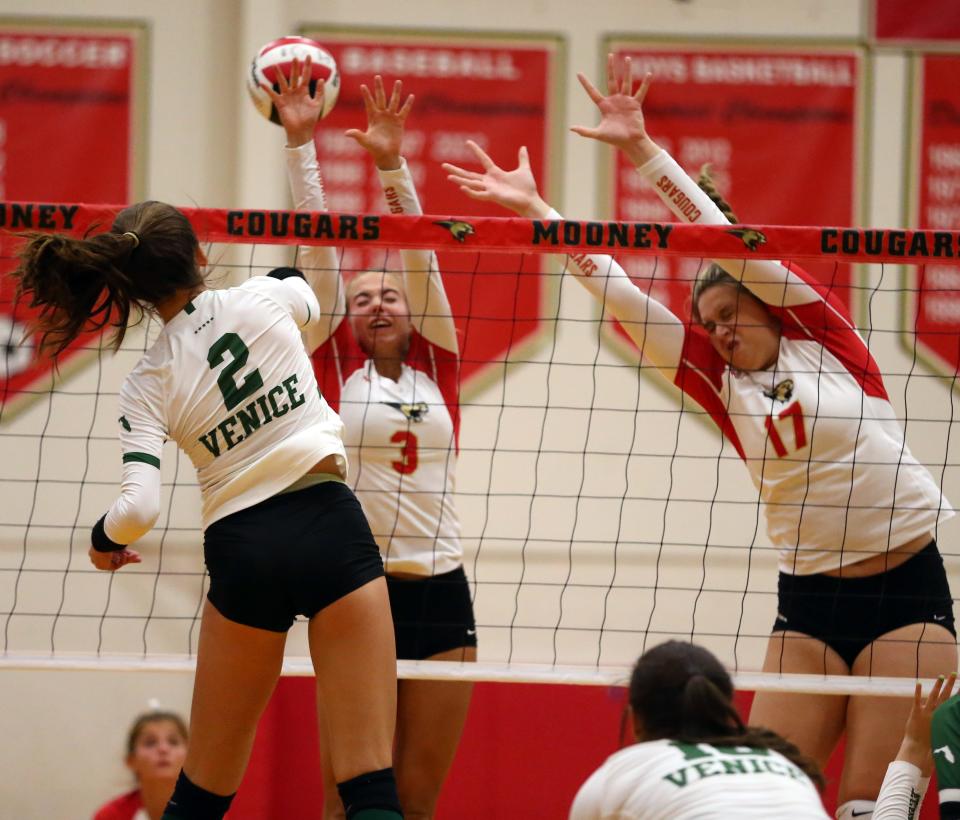 Summer Kohler of Venice High hits the ball past the Cardinal Mooney Catholic block of Gracie Page (3) and Alexa Picciano (17) during Tuesday night's match at Patterson Pavilion in Sarasota. Venice won 3-2 (25-19, 23-25, 25-20, 18-25, 15-9).