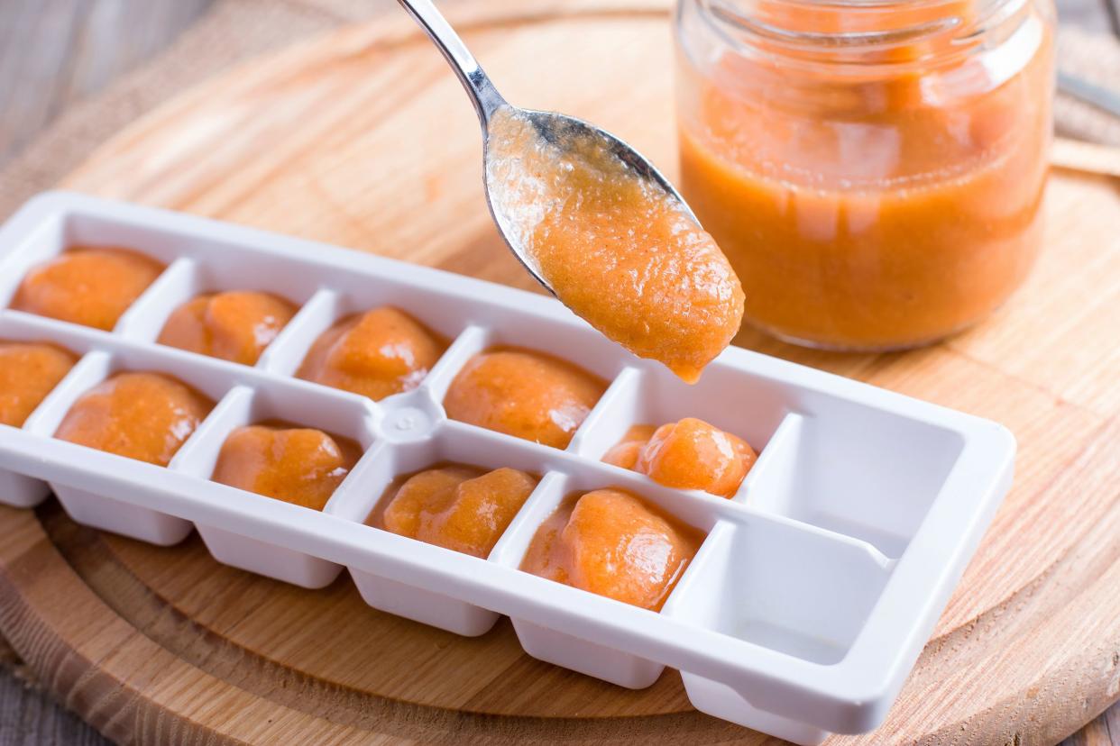 ice tray with fresh fruit puree on wooden background