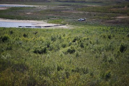 People drive a truck over a part of the lake bed that was formerly underwater to reach a dock at Lake Casitas in Ojai, California, April 16, 2015. REUTERS/Lucy Nicholson