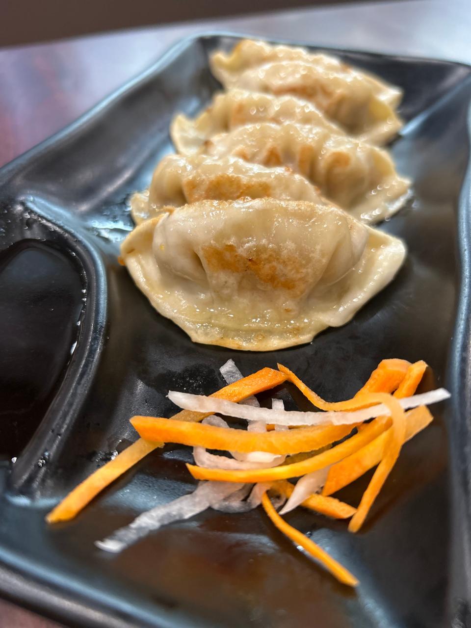 Gyoza dumplings are pan-seared and served with dipping sauce at Noodle King.