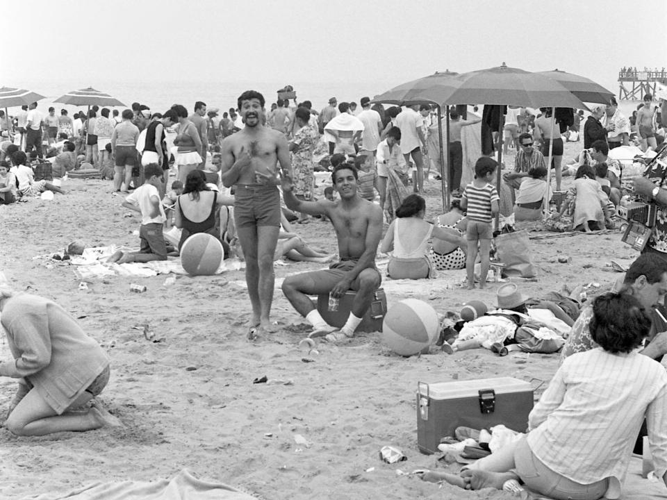 A pair of unidentified men in shorts pose for the camera on the crowded Coney Island Beach on July 4, 1968