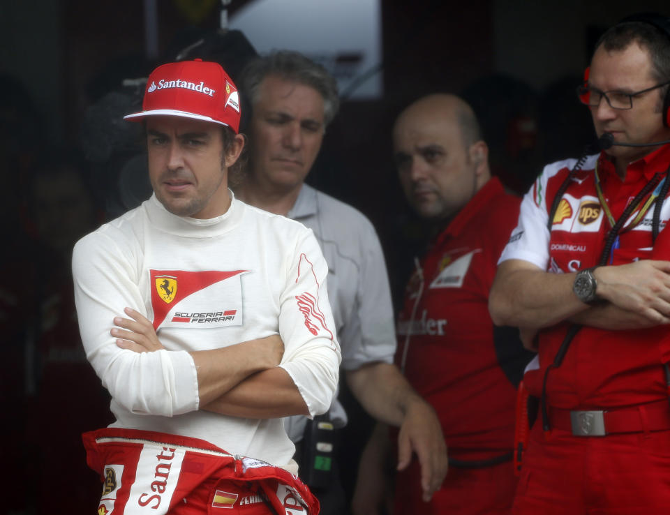 Ferrari driver Fernando Alonso, left, of Spain waits in his team garage due to a rain-delayed of the qualifying session for Sunday's Malaysian Formula One Grand Prix at Sepang International Circuit in Sepang, Malaysia, Saturday, March 29, 2014. (AP Photo/Peter Lim, Pool)