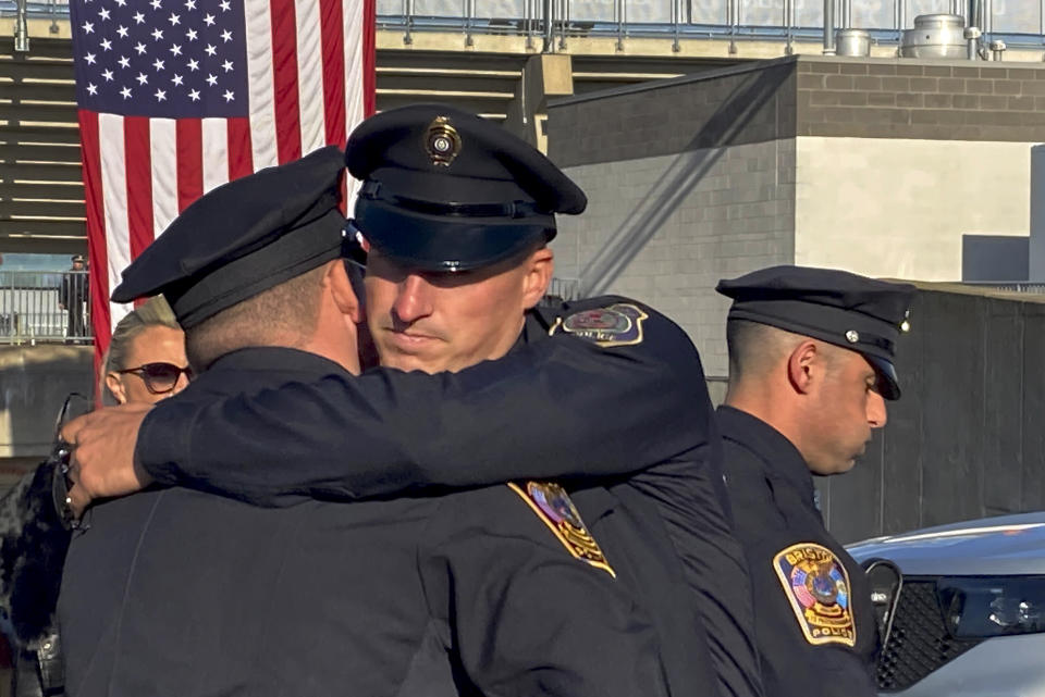 Two Bristol Police department officers hug before a joint police funeral, Friday, Oct. 21, 2022, in East Hartford, Conn. Thousands of police officers from around the country have gathered in a football stadium in Connecticut for a joint funeral for Bristol officers Dustin DeMonte and Alex Hamzy who were shot to death in an apparent ambush on Oct. 12. (AP Photo/David Collins)