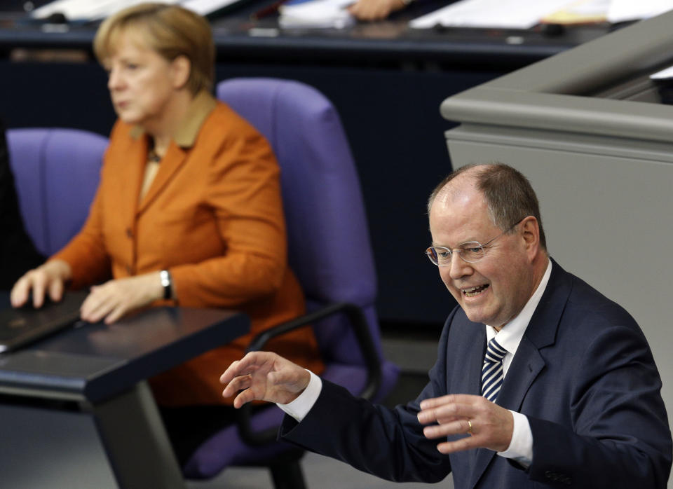 German Chancellor Angela Merkel, visible in background, attends the speech of Peer Steinbrueck, the top candidate of the German Social Democratic Party for the federal elections in 2013, during a meeting of the German Federal Parliament, Bundestag, in Berlin, Germany, Thursday, Oct. 18, 2012. (AP Photo/Michael Sohn)