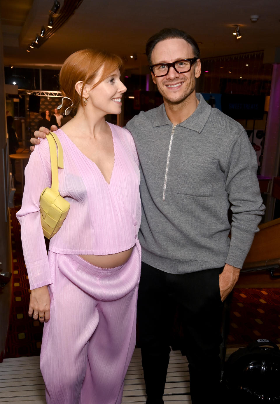 Stacey Dooley wears pink pleated co-ord and yellow bag as she smiles at Kevin Clifton. (Getty Images)