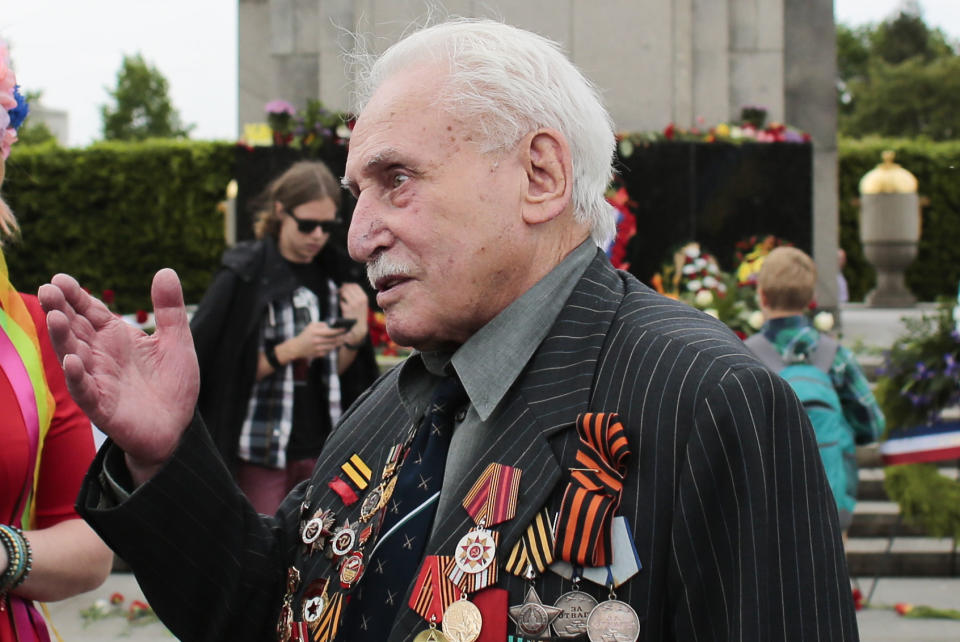 FILE - In this Friday, May 8, 2015 file photo, Soviet war veteran David Dushman, 92, center, speaks to people holding Ukrainian flags as he attends a wreath laying ceremony at the Russian War Memorial in the Tiergarten district of Berlin, Germany. Dushman, the last surviving Allied soldier involved in the liberation of Auschwitz, has died. The Jewish Community of Munich and Upper Bavaria said Sunday, June 6, 2021 that Dushman had died a day earlier in a Munich hospital at the age of 98. As young Red Army soldier, Dushman flattened the forbidding fence around the notorious Nazi death camp with his tank on Jan. 27, 1945. (AP Photo/Markus Schreiber, File)