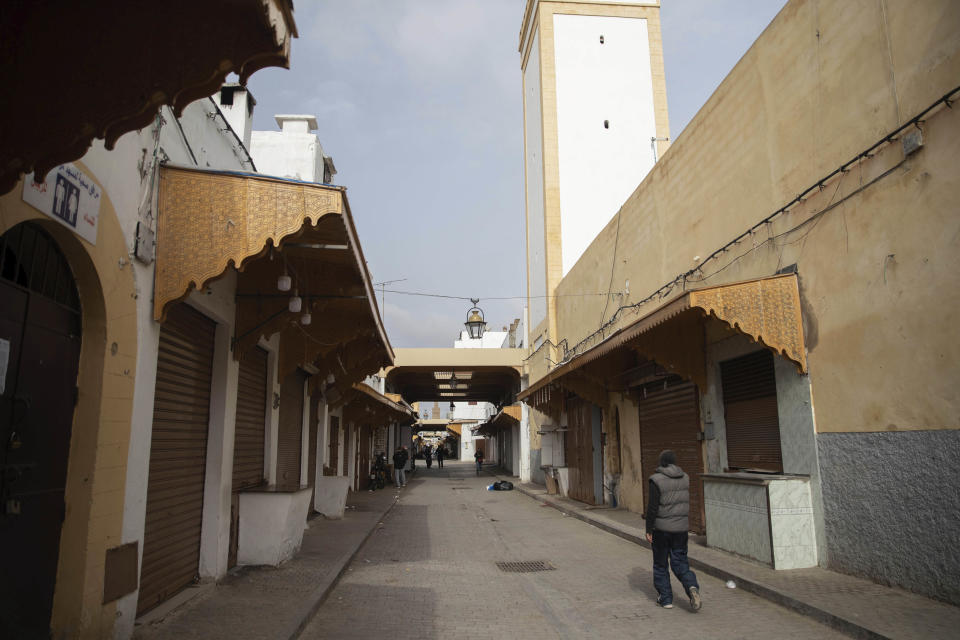 A man walks next to closed shops in the usually-bustling Medina of Rabat, on the day Moroccan authorities called on citizens to limit their movements and comply with self isolation regulations, in Rabat, Morocco, Wednesday, March 18, 2020. For most people, the new coronavirus causes only mild or moderate symptoms, such as fever and cough. For some, especially older adults and people with existing health problems, it can cause more severe illness, including pneumonia. (AP Photo/Mosa'ab Elshamy)