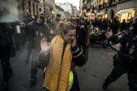 A protester wipes tear gas from her eye at a protest near the Elysee Palace in Paris