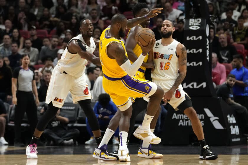 Miami Heat center Bam Adebayo, left, and forward Caleb Martin (16) defend Los Angeles Lakers forward LeBron James (6) during the first half of an NBA basketball game, Wednesday, Dec. 28, 2022, in Miami. (AP Photo/Lynne Sladky)