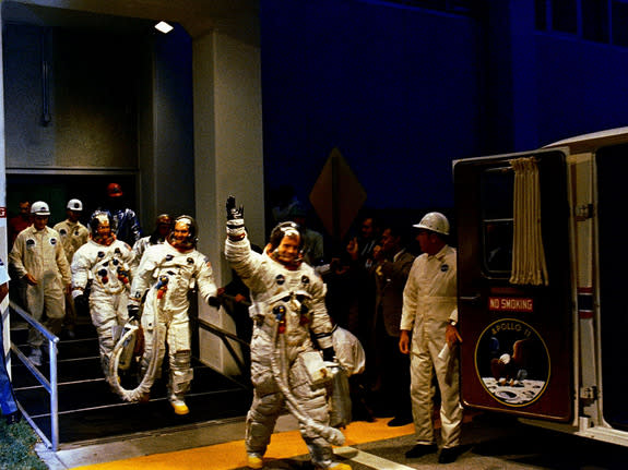 The Apollo 11 crew leaves Kennedy Space Center's Manned Spacecraft Operations Building during the pre-launch countdown. Mission commander Neil Armstrong, command module pilot Michael Collins, and lunar module pilot Buzz Aldrin prepare to ride t
