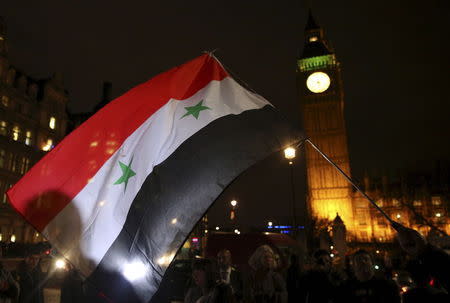 Anti-war protesters wave a Syrian flag as they demonstrate against proposals to bomb Syria outside the Houses of Parliament in London, Britain December 1, 2015. REUTERS/Neil Hall
