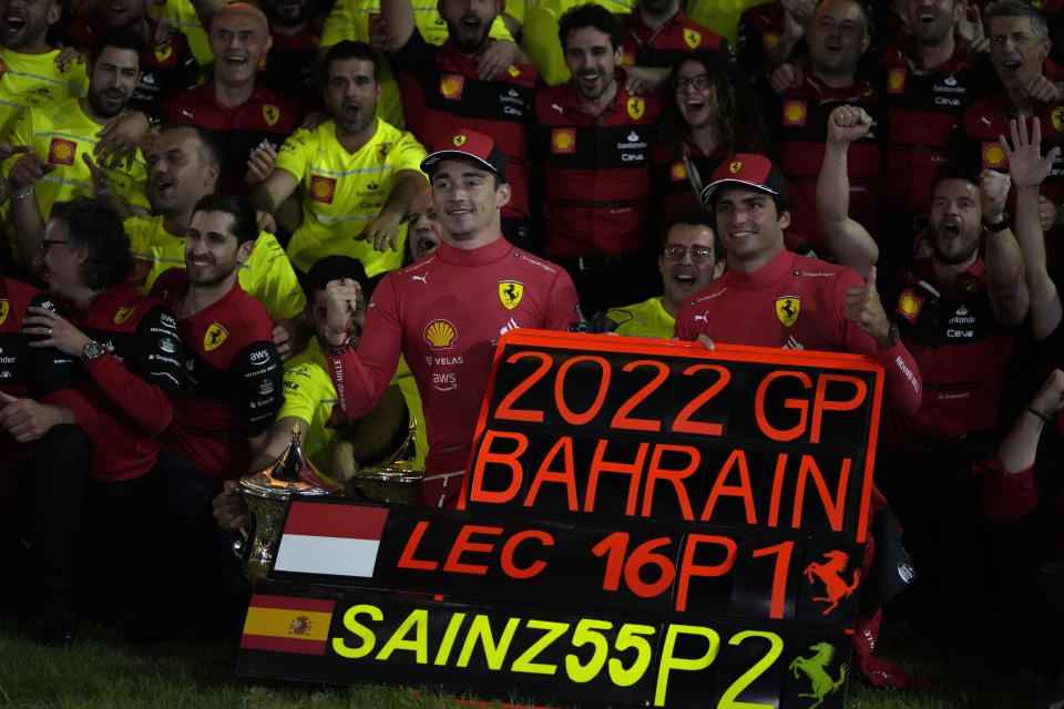 Ferrari driver Charles Leclerc of Monaco, left, and Ferrari driver Carlos Sainz of Spain pose for photograph with team members celebrating winning the first and second positions during the Bahrain Formula One Grand Prix at the Formula One Bahrain International Circuit in Sakhir, Bahrain, Sunday, March 20, 2022. (AP Photo/Hassan Ammar)