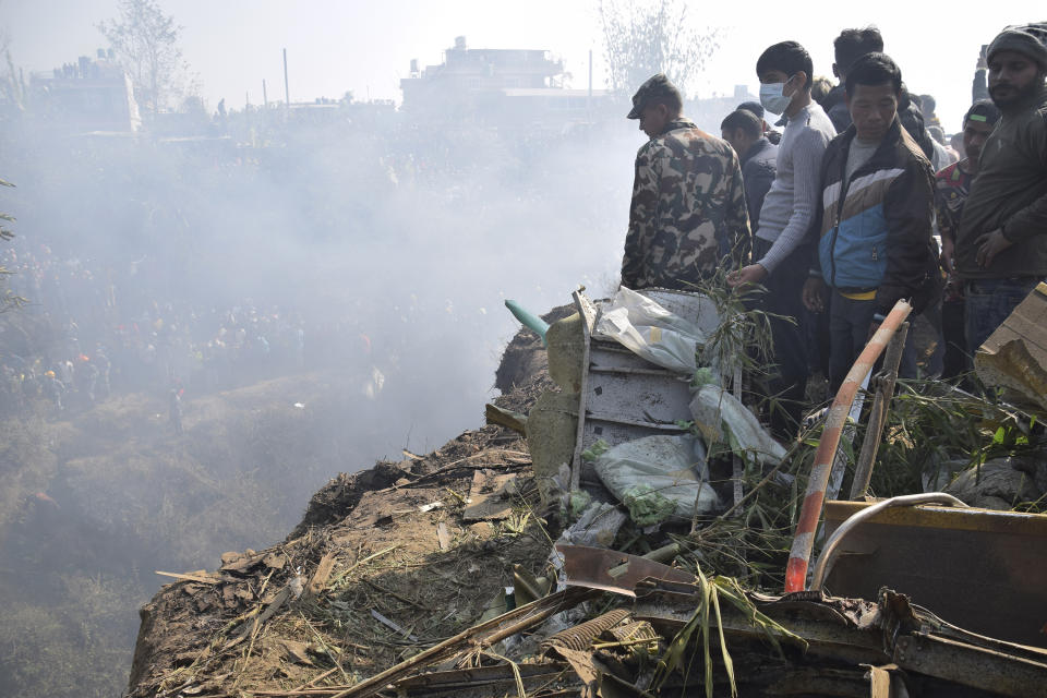 Nepalese rescue workers and civilians gather around the wreckage of a passenger plane that crashed in Pokhara, Nepal, Sunday, Jan. 15, 2023. Authorities in Nepal said 68 people have been confirmed dead after a regional passenger plane with 72 aboard crashed into a gorge while landing at a newly opened airport in the resort town of Pokhara. It's the country's deadliest airplane accident in three decades. (AP Photo/Krishna Mani Baral)