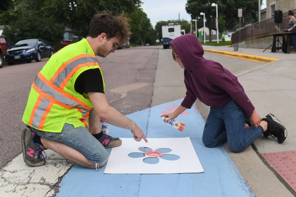 Fourth grade student Ella Franzna (right) learns how to spray paint stencils from local artist Zach DeBoer (left) at Terry Redlin Elementary School on Tuesday, Aug. 15, 2023.