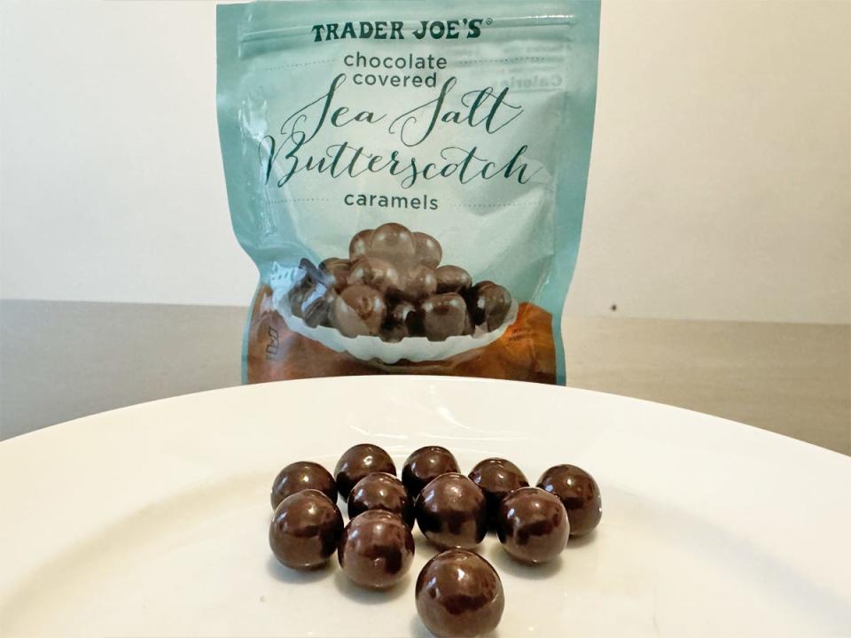 Blue bag of Trader Joe's chocolate-covered sea-salt-butterscotch caramels with a plate of round, chocolate caramels in front