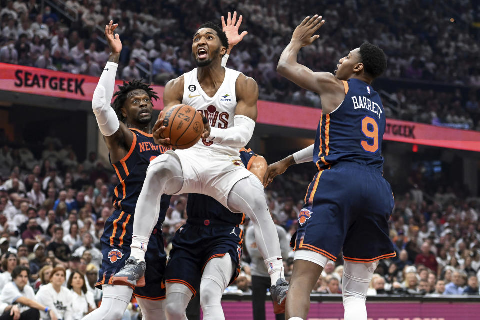 Cleveland Cavaliers' Donovan Mitchell, center, drives to the basket against New York Knicks' Julius Randle, left, and RJ Barrett during the first half of Game 1 in a first-round NBA basketball playoffs series Saturday, April 15, 2023, in Cleveland. (AP Photo/Nick Cammett)