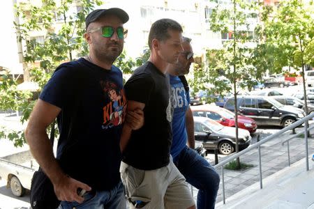 A Russian man (C) suspected of running a money laundering operation is escorted by plain-clothes police officers to a court in Thessaloniki, Greece July 26, 2017. REUTERS/Alexandros Avramidis