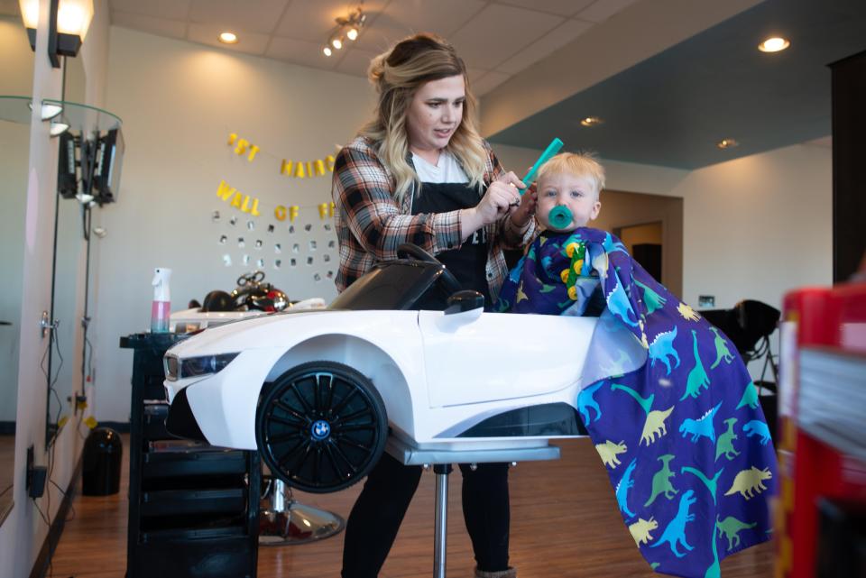 Amanda Rice, owner of Clipeez in Topeka, Kan., combs and clips 1-year-old Ryder Singer during his first haircut.