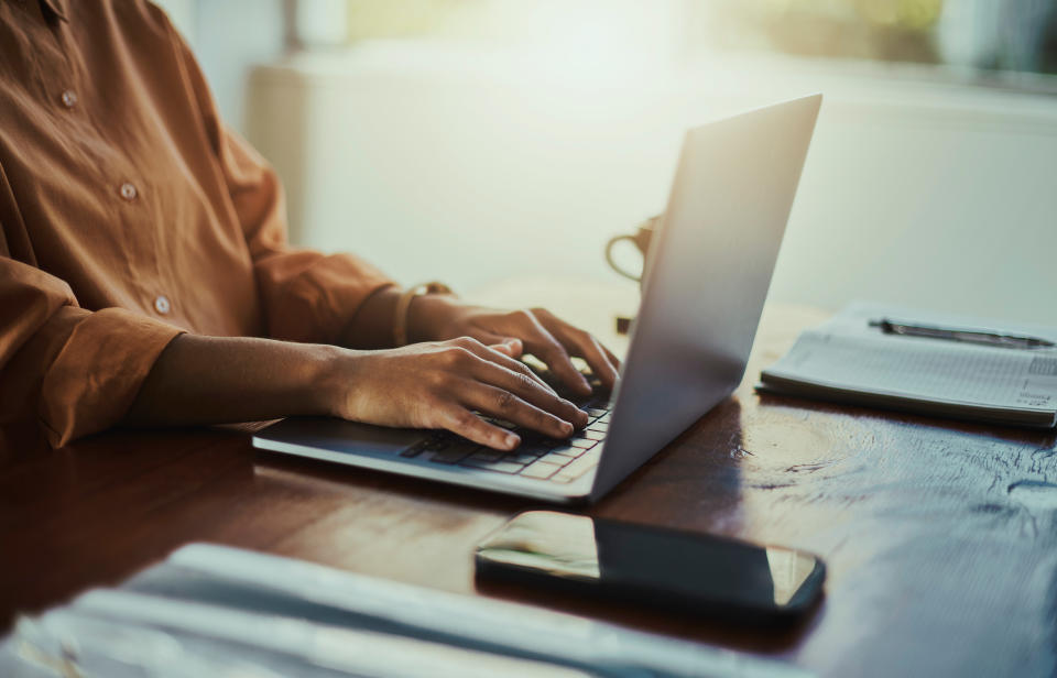 Desk, laptop and hands of black woman typing on keyboard for report, website research and writing email. Productivity, office and girl on computer for planning, marketing review and business strategy