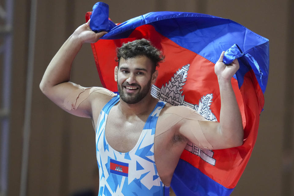 Cambodia's Sari Mo celebrates with his country's flag after winning against Thailand's Sirithahan Atthaphol during their men's Greco-Roman 97-kilogram final wrestling match at the 32nd Southeast Asian Games in Phnom Penh, Cambodia, Sunday, May 14, 2023. (AP Photo/Tatan Syuflana)