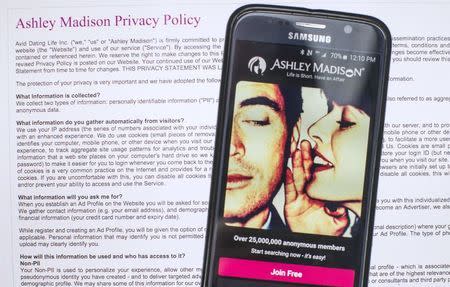 A photo illustration shows the privacy policy of the Ashley Madison website seen behind a smartphone running the Ashley Madison app in Toronto, August 20, 2015. /Mark Blinch