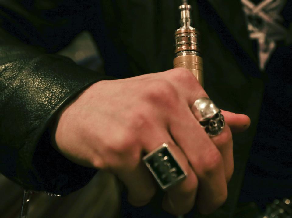 In this Feb. 20, 2014 photo, Will Hopkins holds his vaping device at the Henley Vaporium in New York. E-cigarettes are usually made of metal parts combined with plastic or glass and come in a variety of shapes and sizes. They heat the liquid nicotine solution, creating vapor that quickly dissipates when exhaled. (AP Photo/Frank Franklin II)