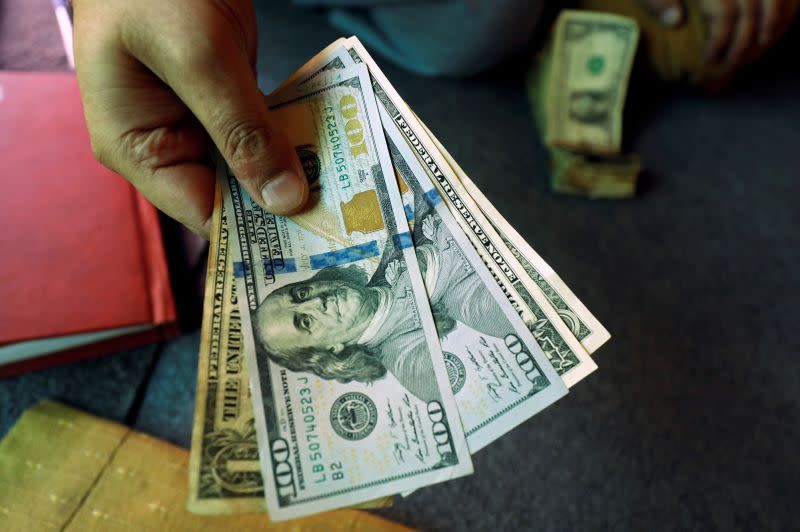 A trader shows U.S. dollar notes at a currency exchange booth in Peshawar