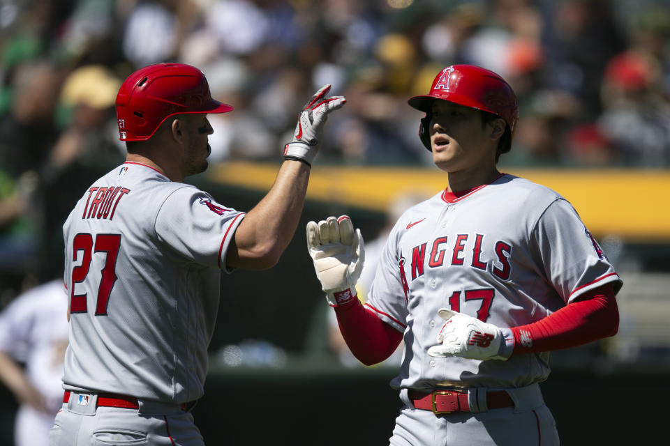 Los Angeles Angels' Mike Trout (27) greets teammate Shohei Ohtani after they scored against the Oakland Athletics during the third inning of a baseball game, Saturday, April 1, 2023, in Oakland, Calif. (AP Photo/D. Ross Cameron)