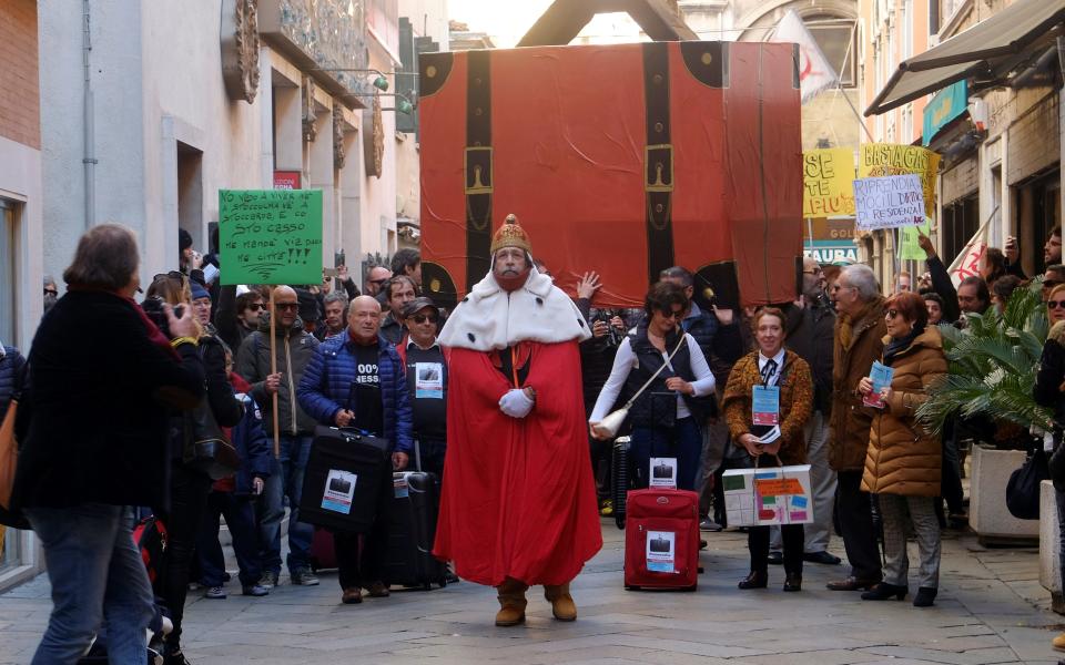 Venetians carry a huge suitcase in a symbolic protest about the number of residents packing their bags and leaving the lagoon city for good. - Credit: Manuel Silvestri/Reuters