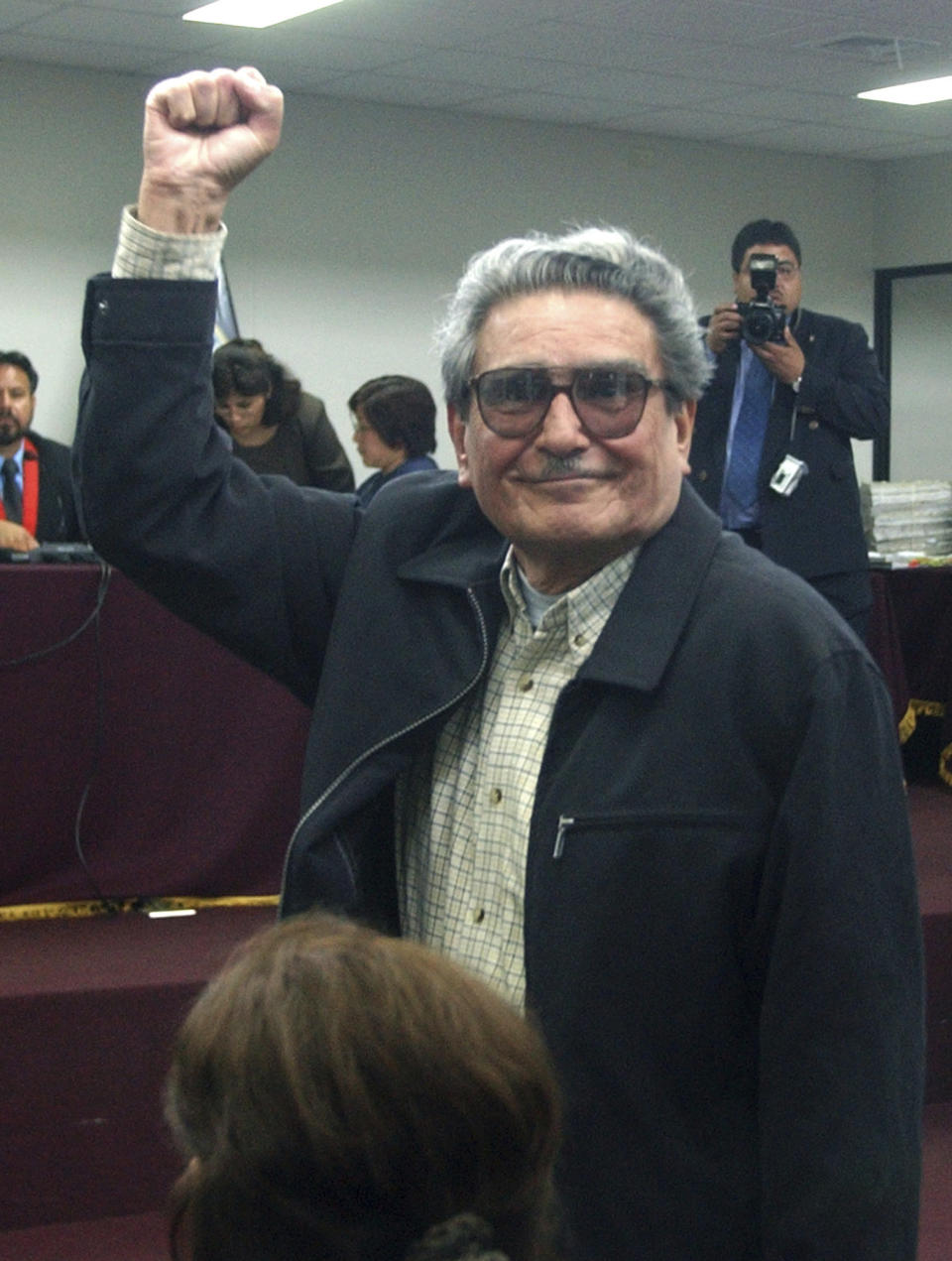 FILE - In this in this Nov. 5, 2004 file photo, Abimael Guzman, the founder and former leader of the Shining Path guerrilla movement, raises his arm during the first day of his civilian trial at the Naval Base in Callao, Peru. The Peruvian government reported Saturday, Sept. 11, 2021, that Guzman died after an illness. (AP Photo/Martin Mejia, File)