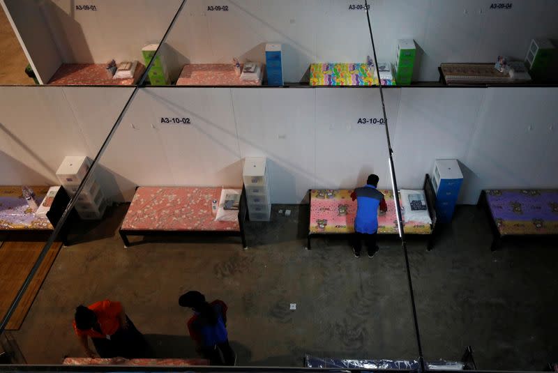 Workers prepare the beds at Changi Exhibition Centre which has been repurposed into a community isolation facility that will house recovering or early COVID-19 patients with mild symptoms, in Singapore