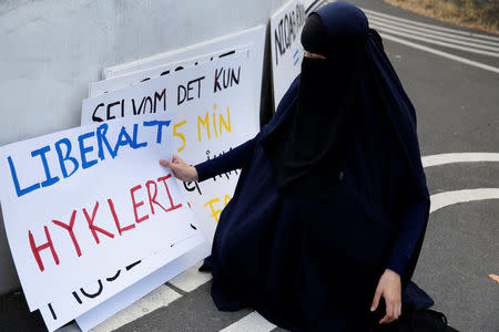 A woman in a niqab collects signs at a demonstration against the Danish face veil ban in Copenhagen, Denmark, August 1, 2018. REUTERS/Andrew Kelly