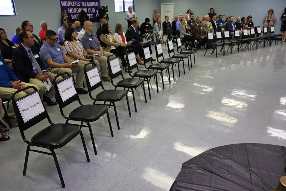 Empty chairs representing 18 workers who died on the job in 2021 fill the first row at the eighth annual Workers' Memorial Observance Ceremony at the Northeast Florida Safety Council building in Jacksonville. Dozens gathered to commemorate them, including OSHA officials and business association leaders.