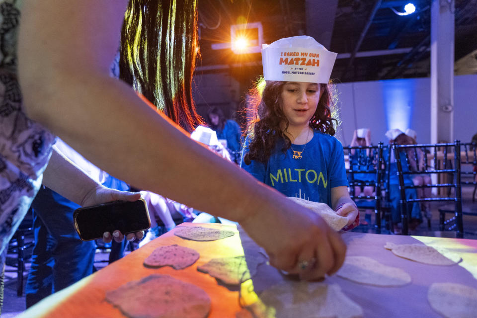 Charlotte Gleicher, 7, a first grader at Milton Gottesman Jewish Day School of the Nation's Capital, brings up dough to be baked into matzah that she made during a "Matzah Factory" event at the JCrafts Center for Jewish Life and Tradition in Rockville, Md., Thursday, April 18, 2024, ahead of the Passover holiday which begins next Monday evening. To be kosher for Passover, which begins next Monday evening, the dough has to be prepared and cooked all within 18 minutes and not allowed to rise. (AP Photo/Jacquelyn Martin)