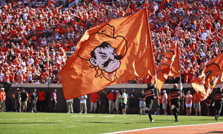 An Oklahoma State cheerleader carries a Pistol Pete flag.