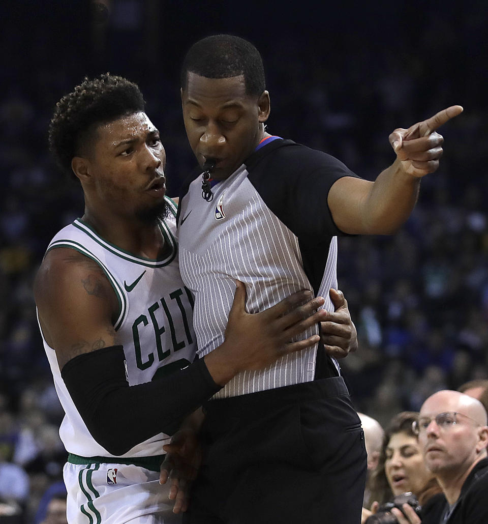 Boston Celtics' Marcus Smart, left, embraces referee Mitchell Ervin during the first half of the team's NBA basketball game against the Golden State Warriors on tuesday, March 5, 2019, in Oakland, Calif. (AP Photo/Ben Margot)