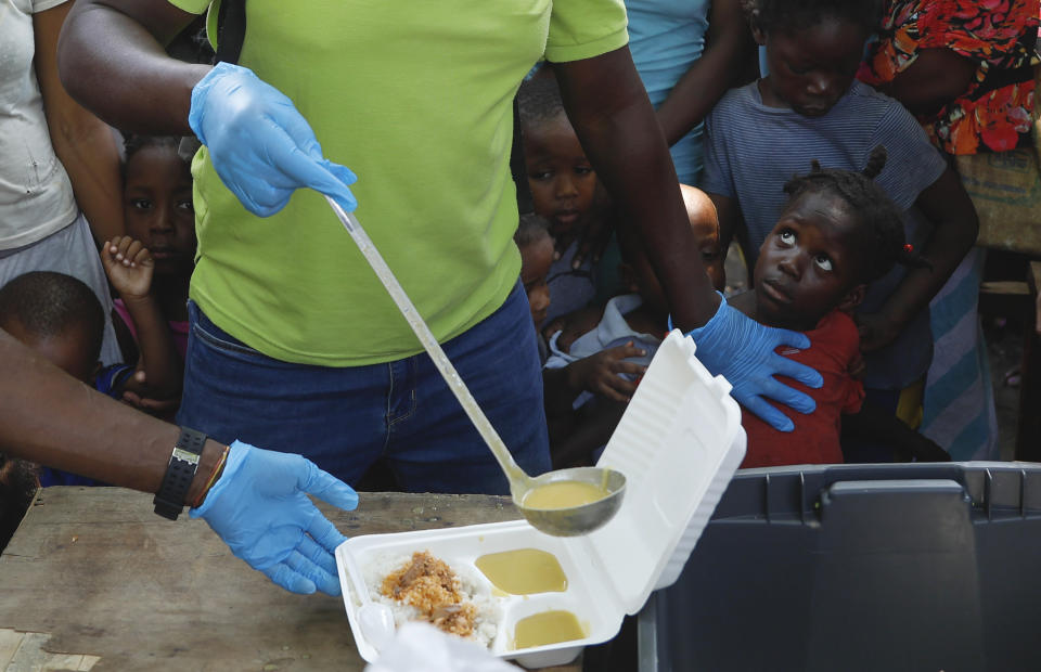 Una persona sirve sopa en un recipiente mientras varios niños hacen fila para recibir comida en un albergue para familias desplazadas por la violencia de las pandillas, en Puerto Príncipe, Haití, el 14 de marzo de 2024. (AP Foto/Odelyn Joseph)