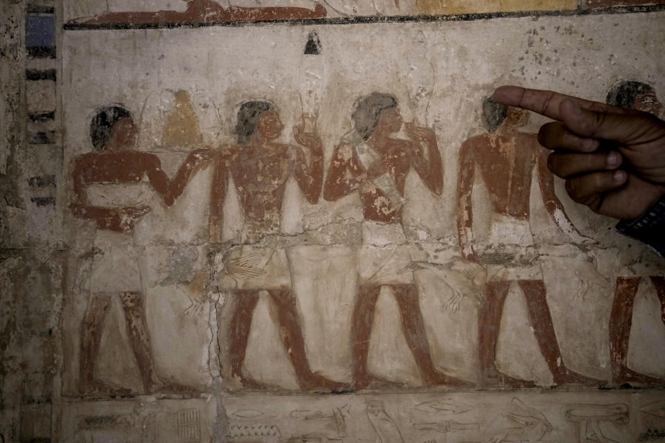 An Egyptian archeologist points at a colored painting showing offering sacrifices at a recently uncovered tomb that was said to belong to a top official of the fifth Dynasty named "Ne Hesut Ba" (2400 BC), at the site of the Step Pyramid of Djoser in Saqqara, 24 kilometers (15 miles) southwest of Cairo, Egypt, Saturday, May 27, 2023. Saqqara is a part of Egypt's ancient capital of Memphis, a UNESCO World Heritage site. (AP Photo/Amr Nabil)