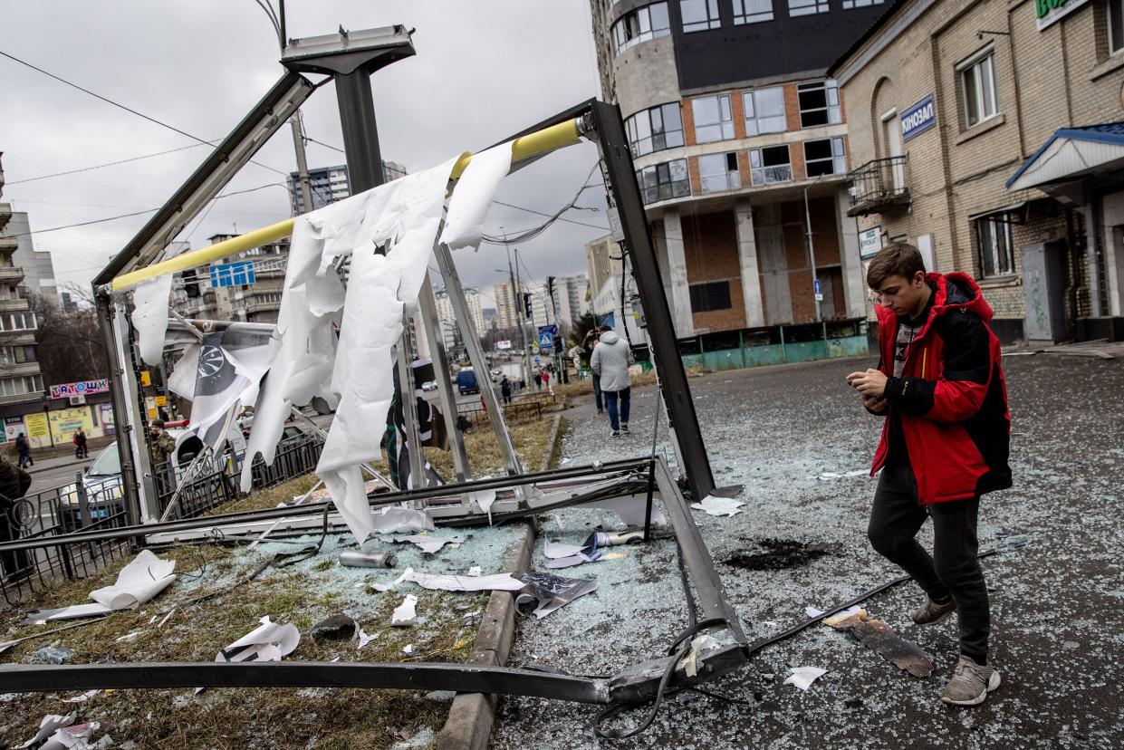People stand around a damaged structure caused by a rocket on Feb. 24, 2022, in Kyiv, Ukraine.