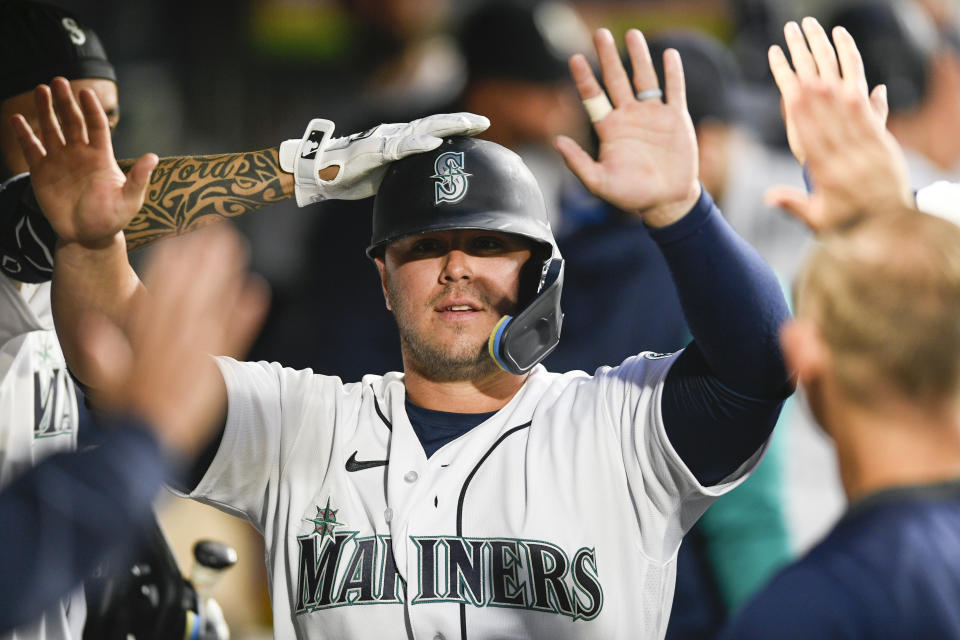 Seattle Mariners' Ty France celebrates with his teammates in the dugout after scoring a run off of Mitch Haniger's sacrifice fly during the first inning of a baseball game against the Texas Rangers, Wednesday, Sept. 28, 2022, in Seattle. (AP Photo/Caean Couto)