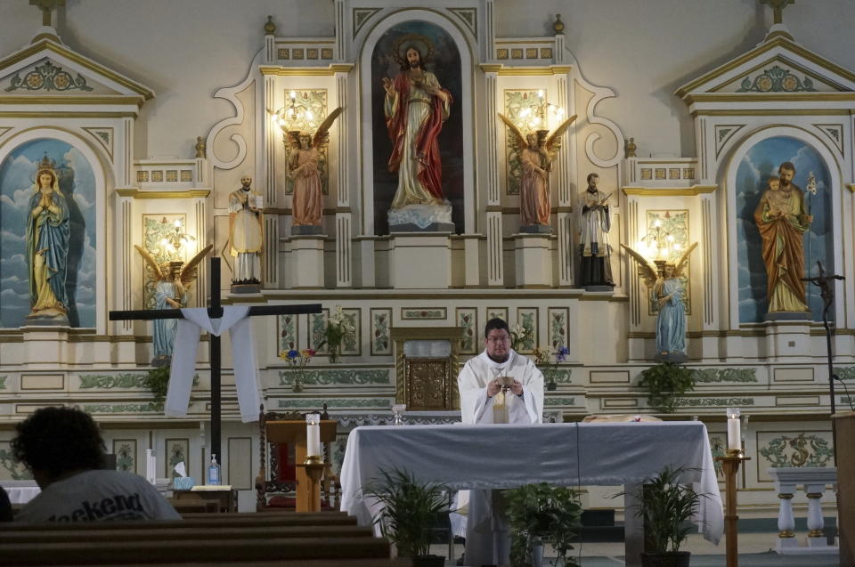 Rev. Daniel Mora offers prayers for migrants during a morning Mass at the Sacred Heart Catholic Church, in downtown El Paso, Thursday, May 11, 2023. The church opened its gym last fall to host up to 140 migrants, but more than a thousand gathered outside it earlier this week, though numbers had dropped to handfuls since then. (AP Photo/Giovanna Dell'Orto)