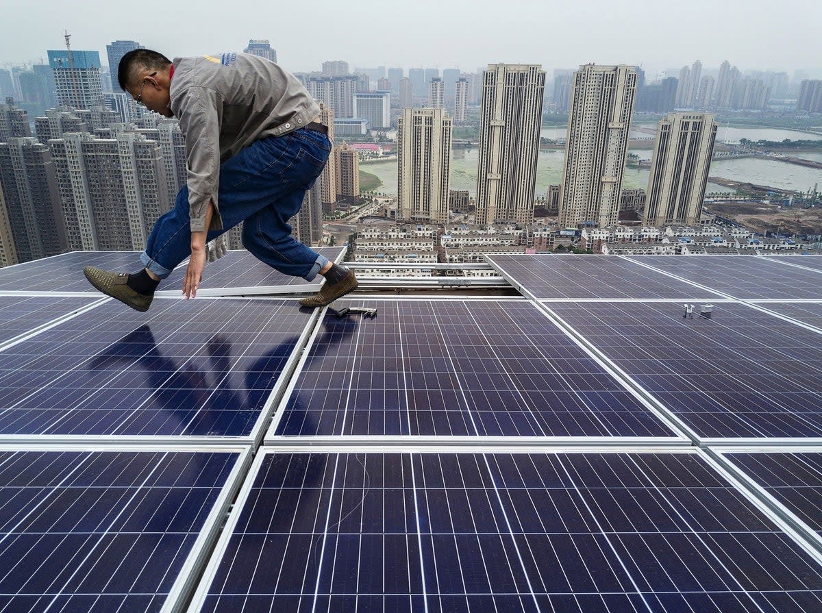 A Chinese worker installing solar panels on the roof of a 47 story building in Wuhan, China, on 15 May, 2017 (Getty Images)
