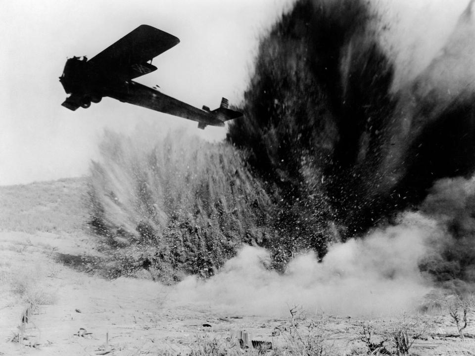An explosion occurs below an airplane on the set of Hell's Angels, directed and produced by Howard Hughes.
