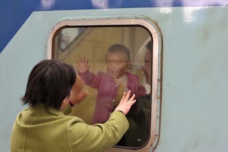 A Chinese baby waves to his mother as he and his father depart from Shanghai's train station, December 29, 2005. REUTERS/Nir Elias