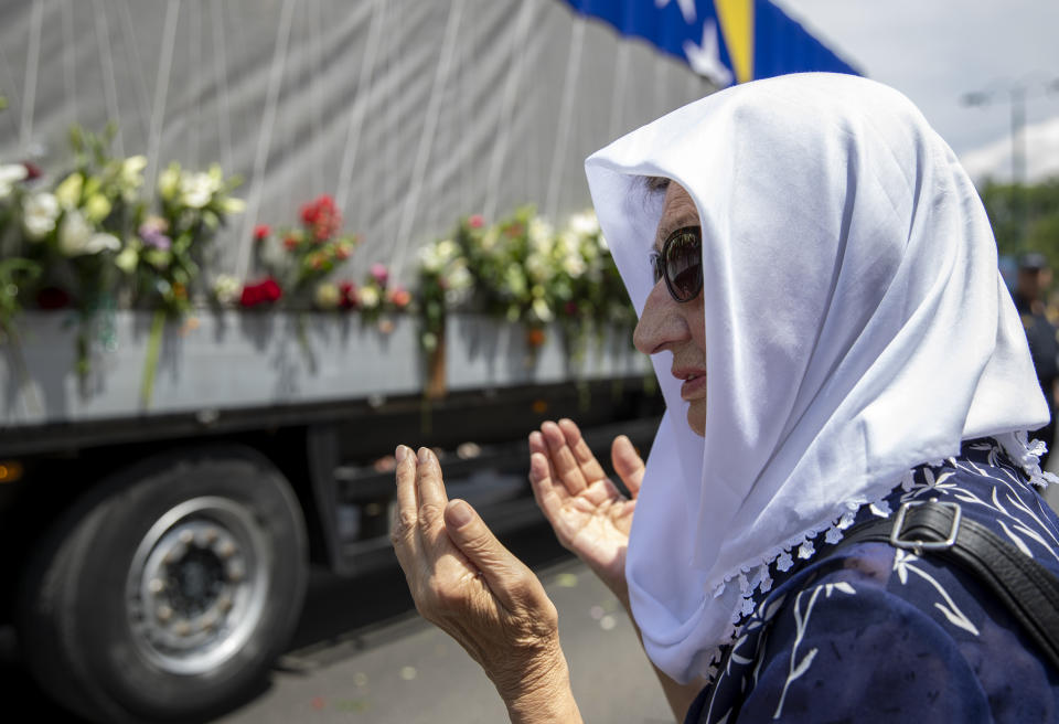 A woman pays respect next to the vehicle carrying the remains of 33 victims of the Srebrenica massacre, in Sarajevo, Bosnia, Tuesday, July 9, 2019. The remains will be buried in Potocari near Srebrenica, on July 11, 2019, 24 years after Serb troops overran the eastern Bosnian Muslim enclave of Srebrenica and executed some 8,000 Muslim men and boys, which international courts have labeled as an act of genocide (AP Photo/Darko Bandic)